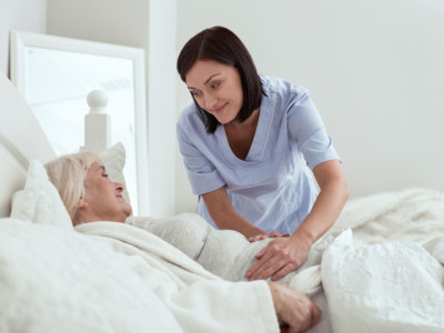 caretaker with senior woman in bed